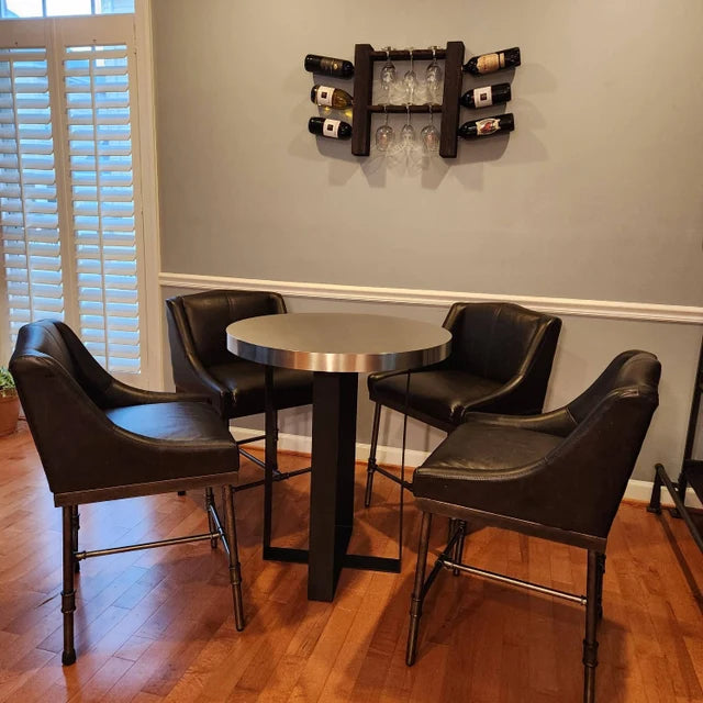 Round metal table with four black leather chairs in a room with a wine rack on the wall.