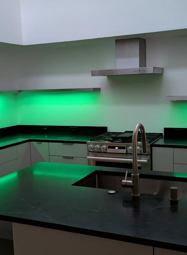 Modern kitchen with green LED lighting on the walls and countertops.